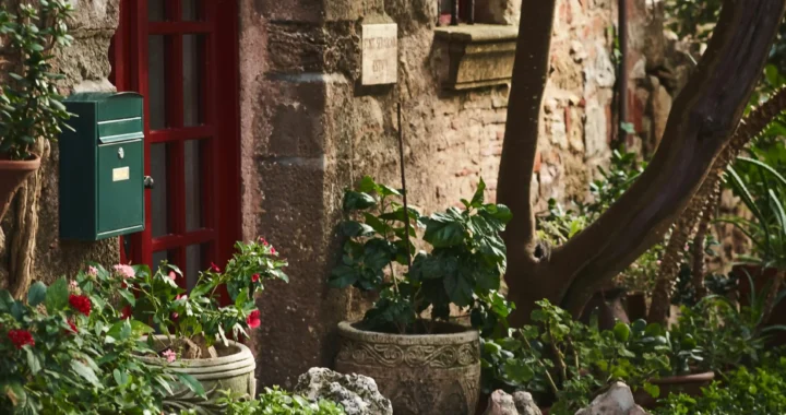 Casa rural de piedra con puerta roja rodeada de vegetación en Girona
